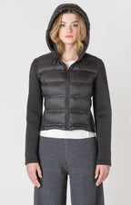 A black puffer jacket with a hood, and thick, stretchy, knitted sleeves.