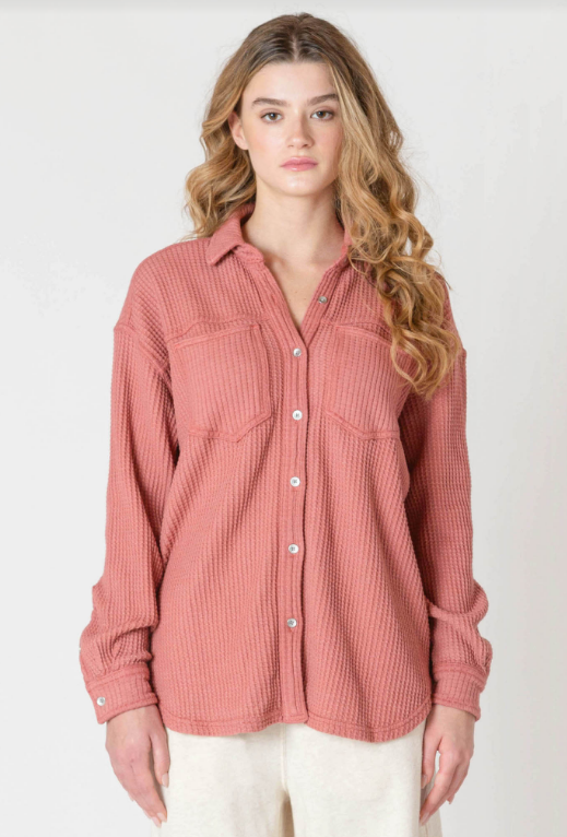Woman wearing a pink ribbed shirt against a white background