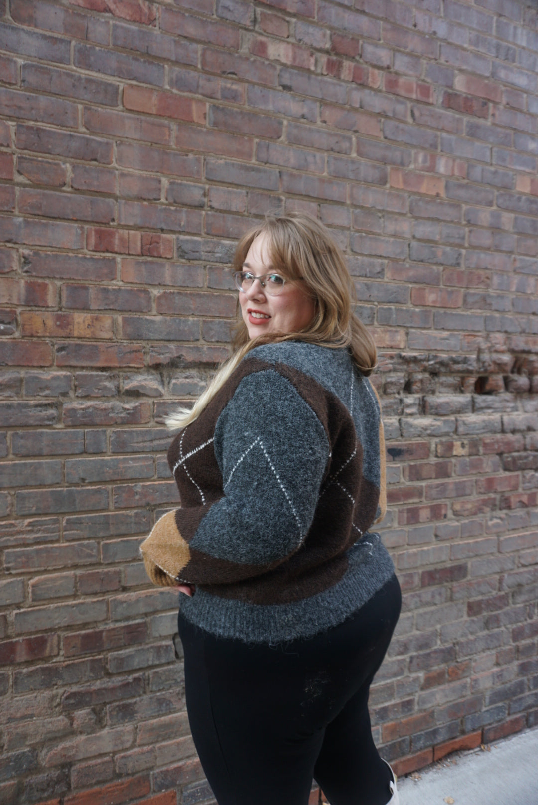 A cozy argyle sweater, with charcoal, tan, brown, and white colors, creating a timeless piece perfect for chilly winter days.