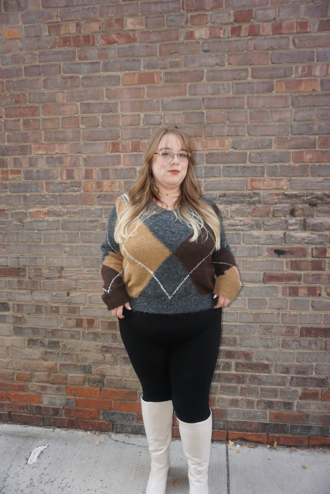 A cozy argyle sweater, with charcoal, tan, brown, and white colors, creating a timeless piece perfect for chilly winter days.