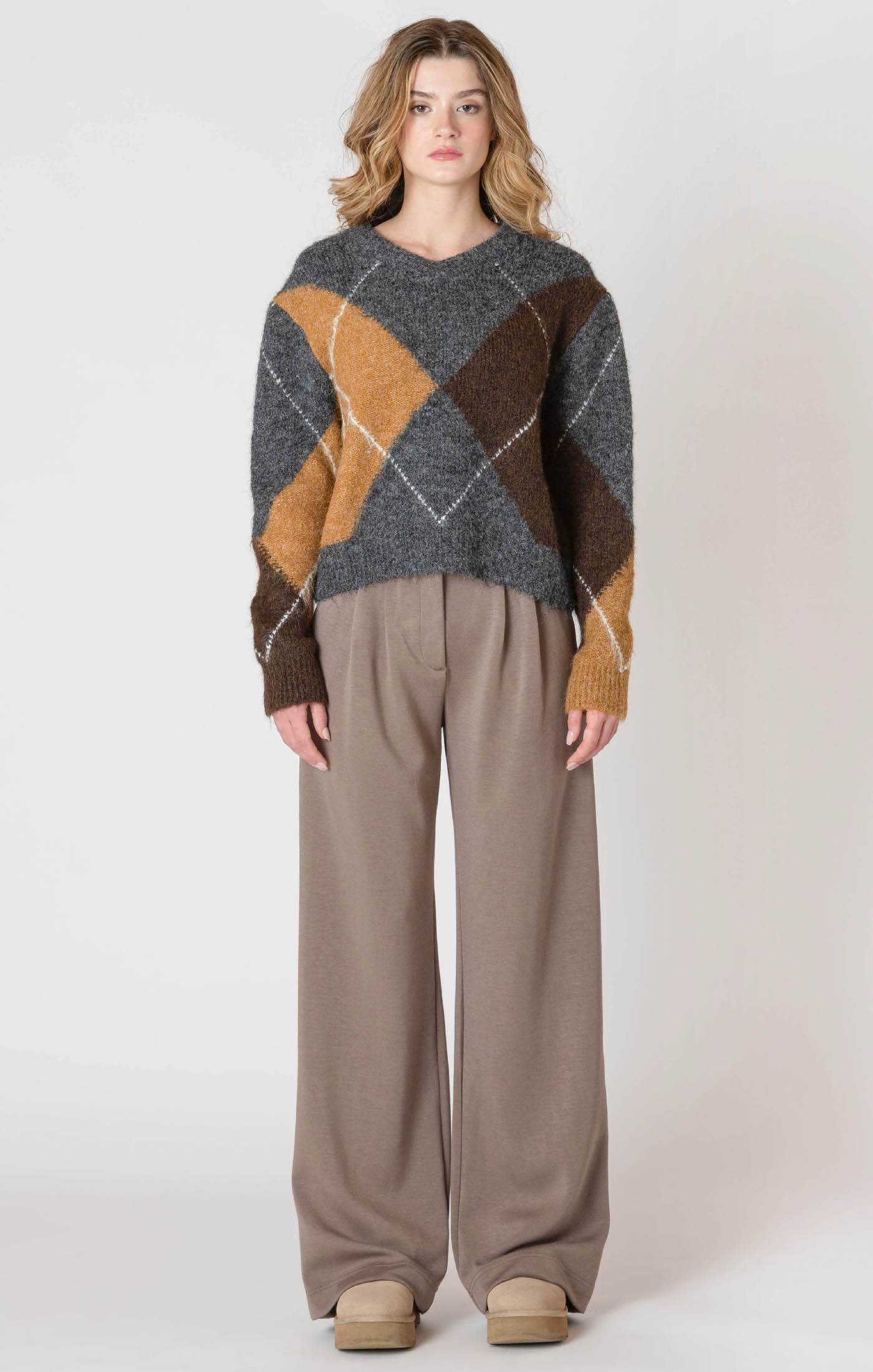 A cozy argyle sweater, with charcoal, tan, brown, and white colors, creating a timeless piece perfect for chilly winter days.