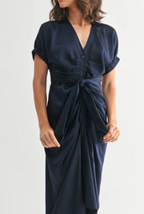 woman wearing a navy blue dress with buttons and a tie on the front with a white background