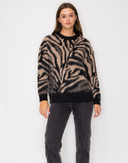 a knit sweater with beige and black zebra like designs on a woman wearing grey jeans