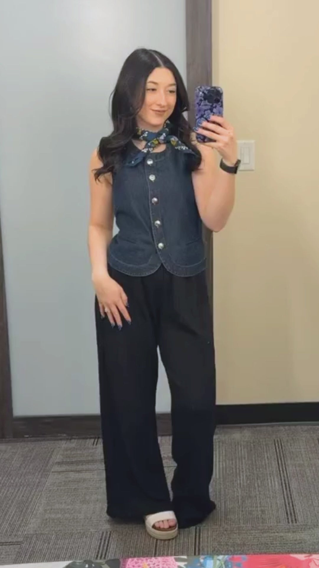 A woman in dark denim top and black pants with a neck scarf.