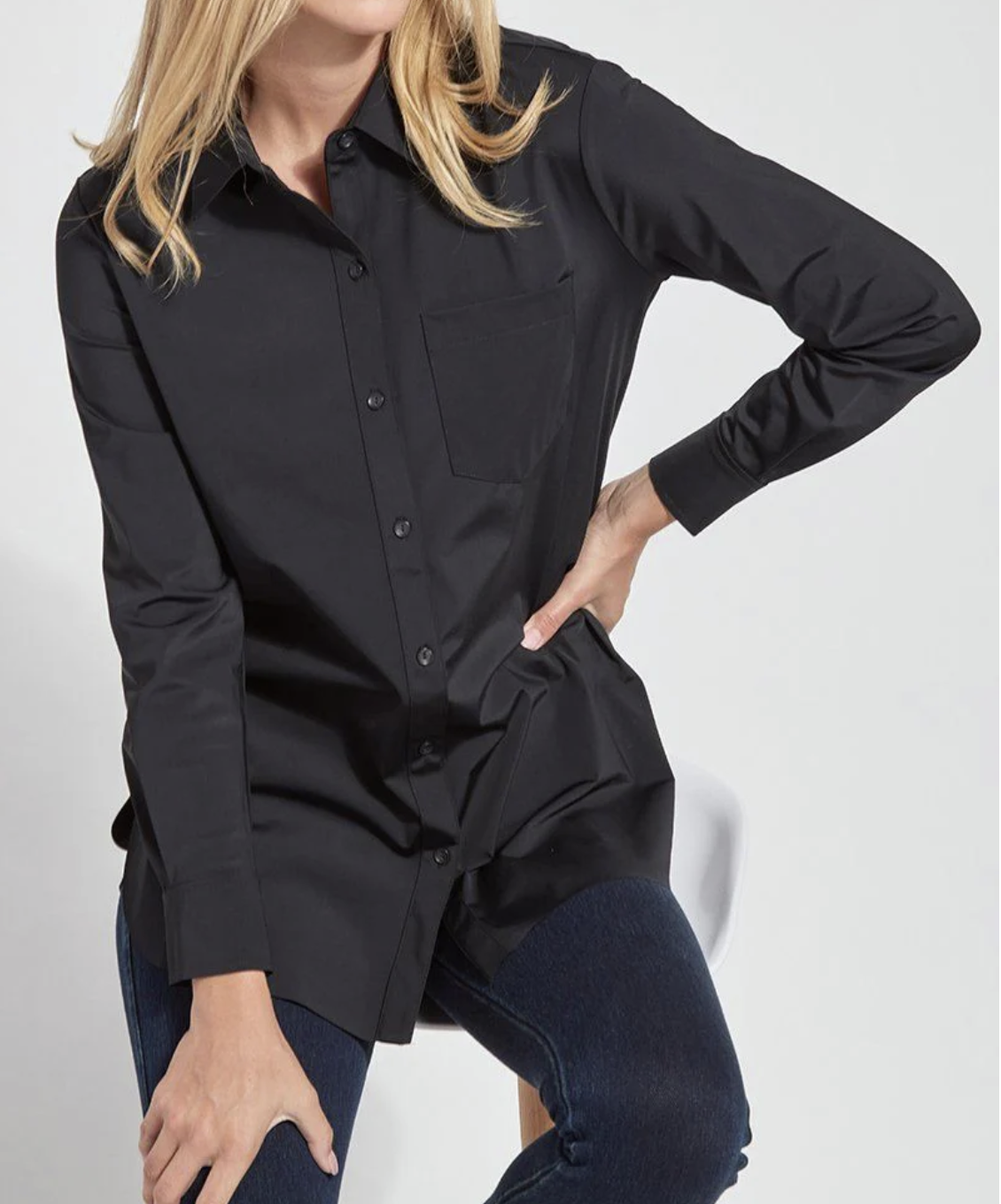 Person wearing a black long-sleeve shirt with a pocket on a white background