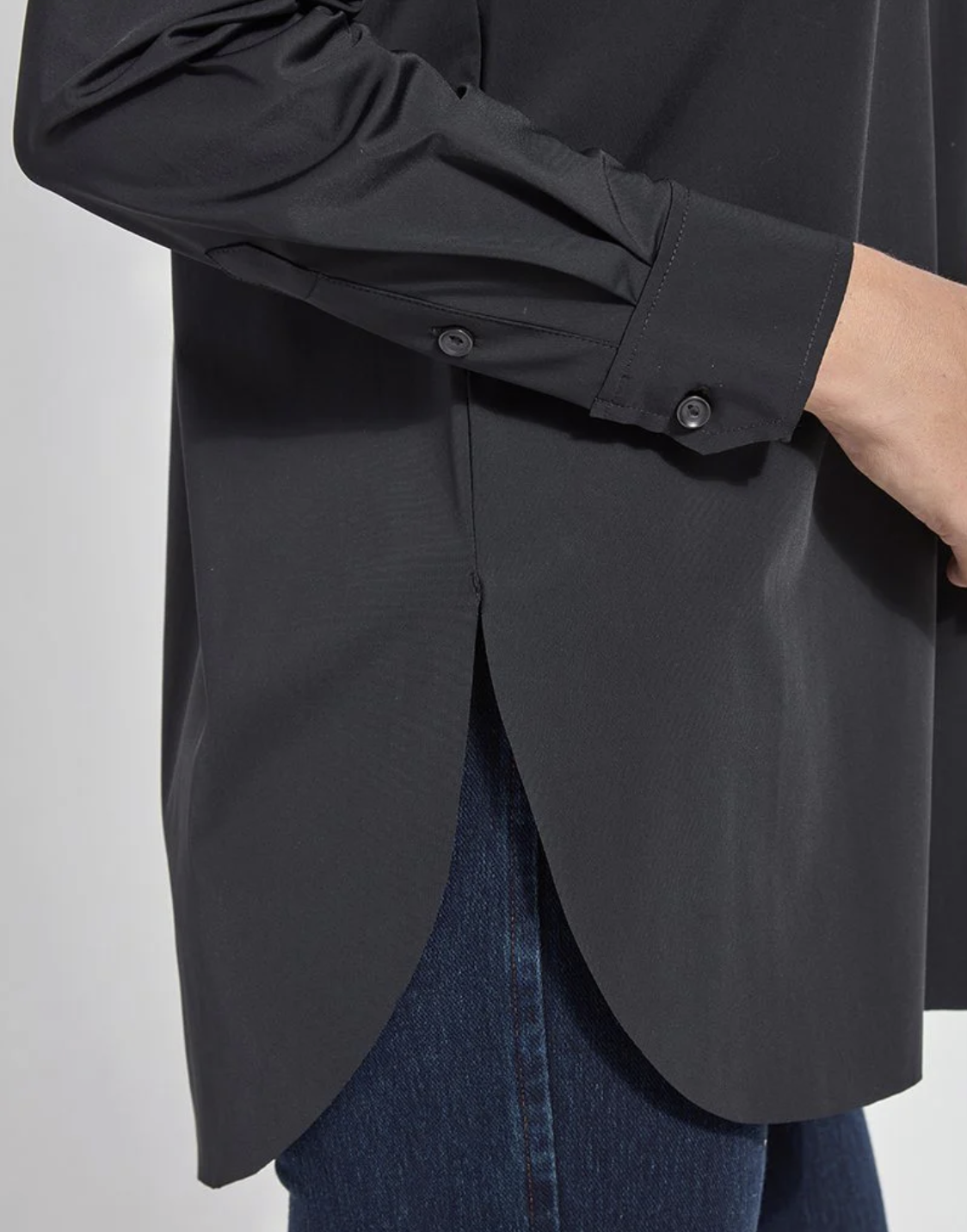 Black shirt with a buttoned front and blue jeans on a plain background